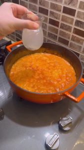 Adding pasta water and shredded kashar cheese to a pink sauce.