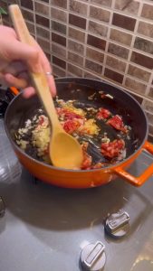 Adding red Turkish pepper paste to a skillet of onions.