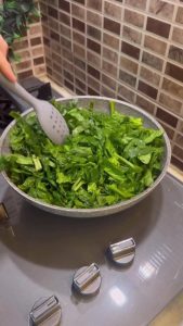 Sautéing spinach and onions in a skillet.