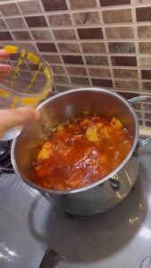 Pouring hot water into a pot of sautéed potatoes and onions.