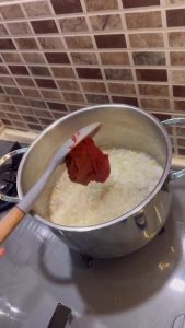 Sautéing onions and tomato paste in a large pot.