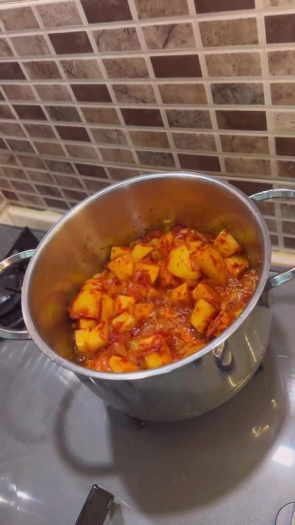Diced potatoes being sautéed with tomato paste in a pot.