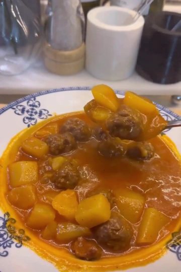 A pot of Turkish meatball stew with diced potatoes in a rich red tomato broth.