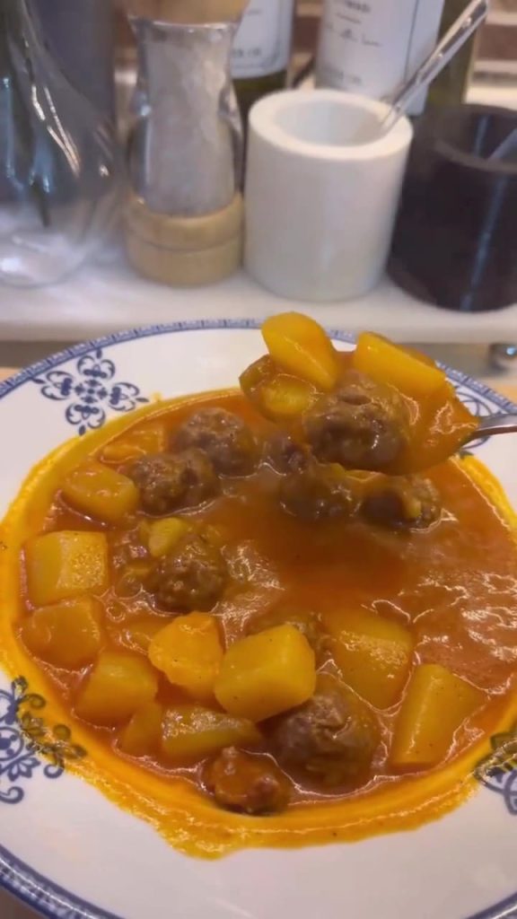 A pot of Turkish meatball stew with diced potatoes in a rich red tomato broth.