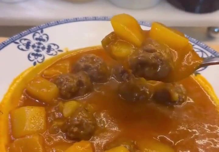 A pot of Turkish meatball stew with diced potatoes in a rich red tomato broth.